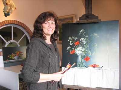 Kunstenares Annna M. Bernardina, staande achter haar schildersezel
